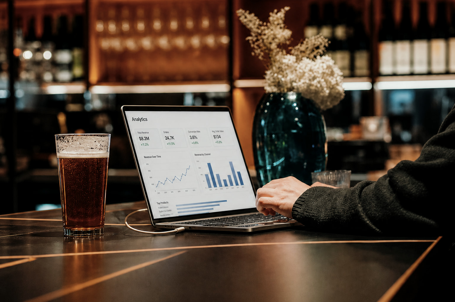 Laptop displaying a business analytics dashboard beside a pint of beer at a bar